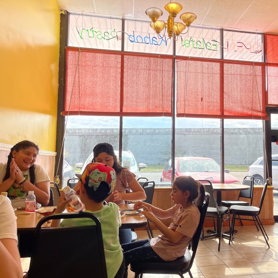 Family enjoying a meal at Habibi's Cafe & Pizzeria, with red blinds covering large windows.