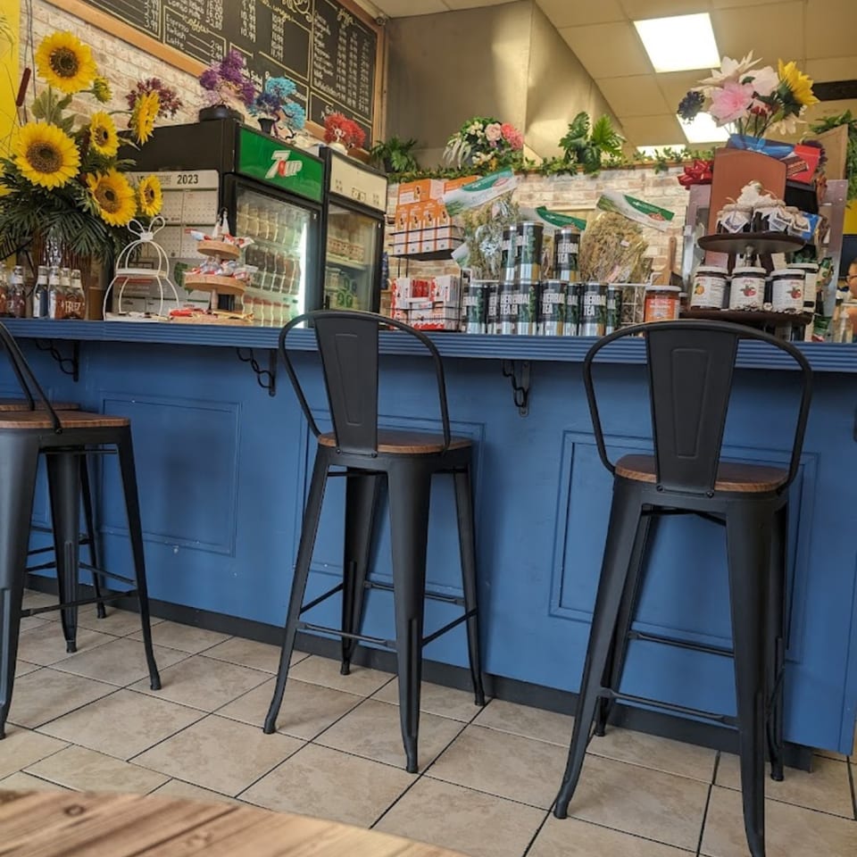 Blue counter with black bar stools, sunflowers, and various products at Habibi's Cafe & Pizzeria.