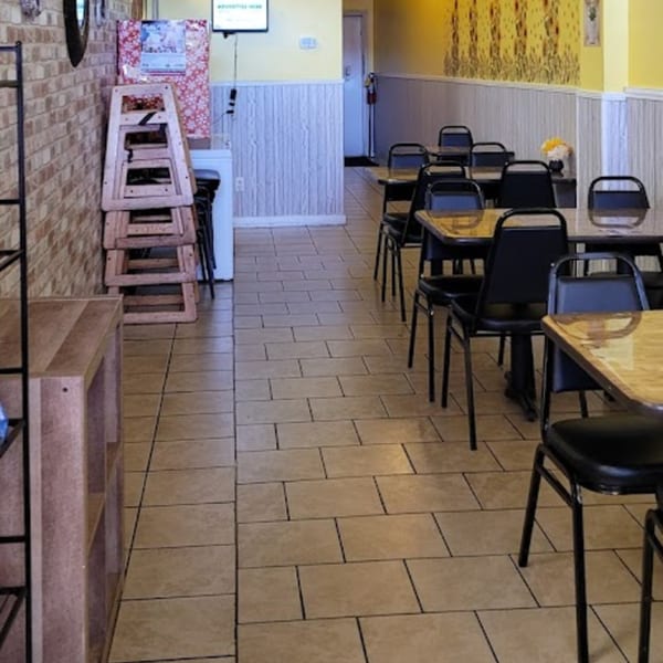 Interior of Habibi's Cafe & Pizzeria with empty tables, chairs, and stacked high chairs.