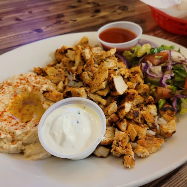 Habibi's Cafe & Pizzeria's chicken shawarma plate with hummus, salad, and two dipping sauces.