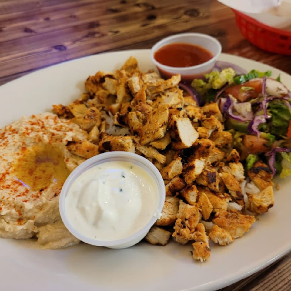 Habibi's Cafe & Pizzeria's chicken shawarma plate with hummus, salad, and two dipping sauces.
