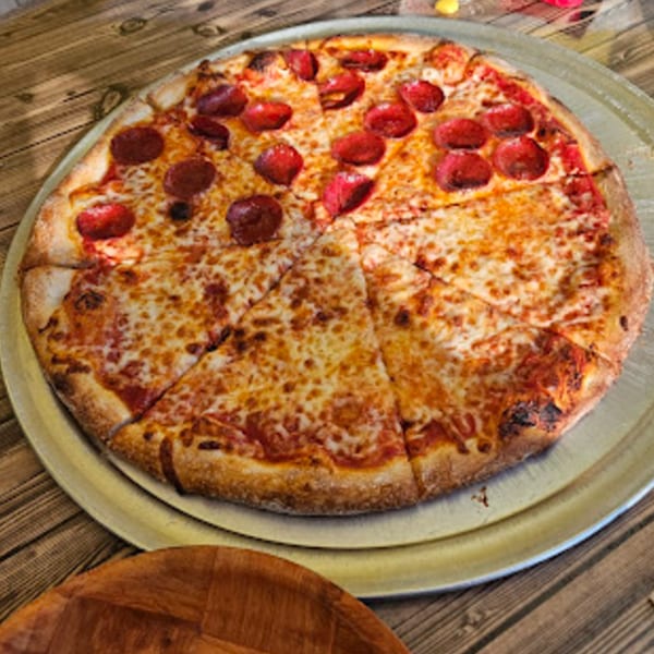 A large Habibi's Cafe & Pizzeria pizza, half pepperoni and half cheese, on a metal tray.