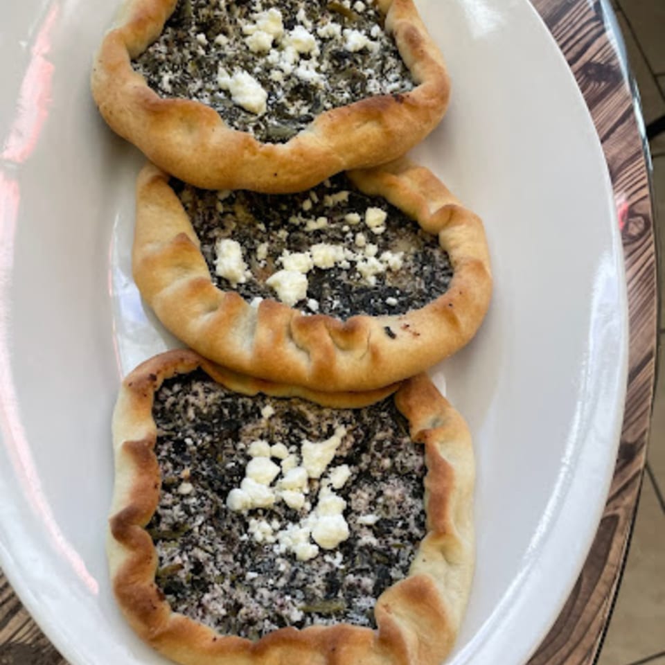 Three spinach and feta fatayer, or savory pies, on a white plate at Habibi's Cafe & Pizzeria.